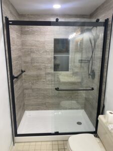 Completed walk-in shower corner with custom shelving and glass door in Powell.