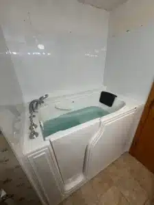 A modern white walk-in tub filled with water featuring an ergonomic headrest and chrome fixtures in a Columbus, OH bathroom remodeling project.