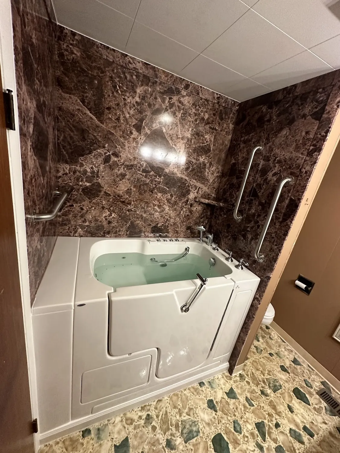 Ella's Bubbles walk-in tub with deep red marble wall surround in Westerville Ohio